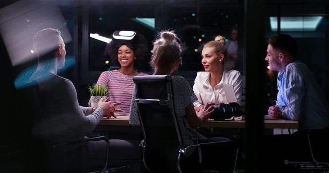 Multiethnic Business team using virtual reality headset in night office meeting  Developers meeting with virtual reality simulator around table in creative office.