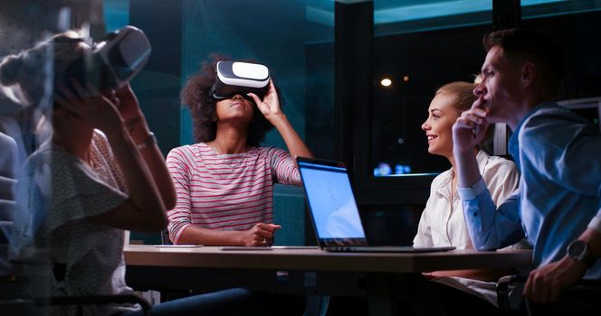 Multiethnic Business team using virtual reality headset in night office meeting  Developers meeting with virtual reality simulator around table in creative office.