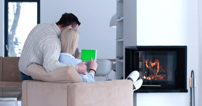 Young couple relaxing at luxurious home with tablet computers reading in the living room on the sofa couch.