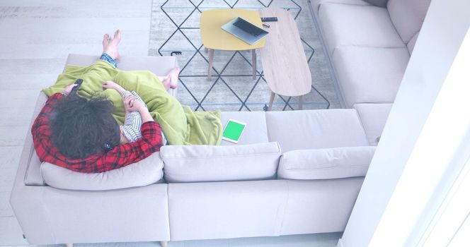 Young couple on the sofa watching television together in their luxury home