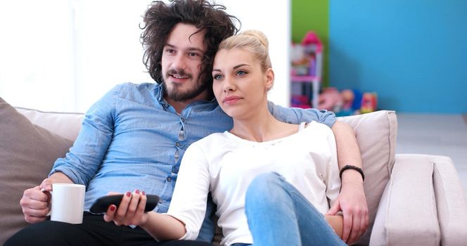 Young couple on the sofa watching television together in their luxury home