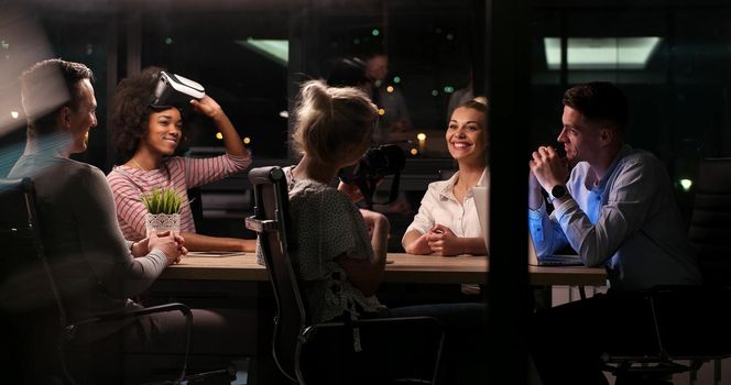 Multiethnic Business team using virtual reality headset in night office meeting  Developers meeting with virtual reality simulator around table in creative office.