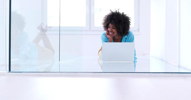 beautiful young african american women using laptop computer on the floor of her luxury home