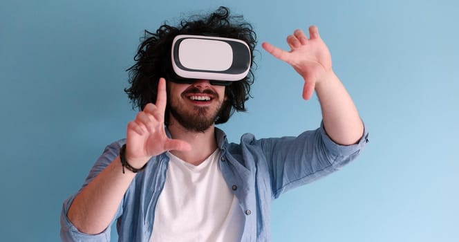 Happy man getting experience using VR headset glasses of virtual reality, isolated on blue background