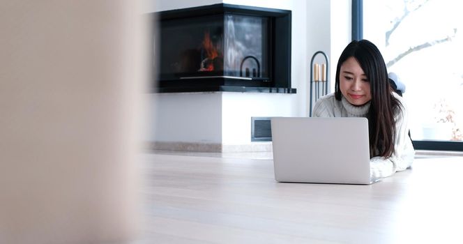 young attractive Asian woman using laptop on floor at home in the living room