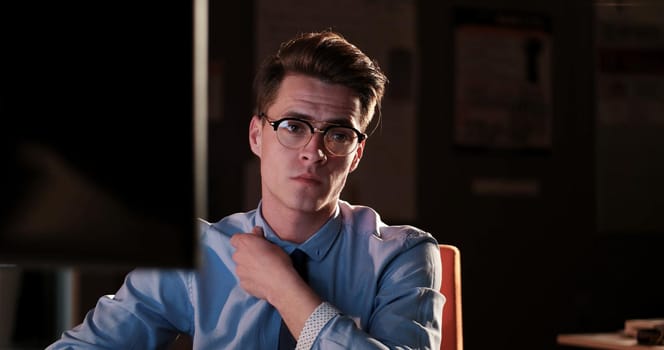 Young man working on computer at night in dark office. The designer works in the later time.