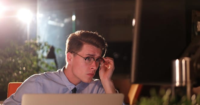 Young man working on computer at night in dark office. The designer works in the later time.