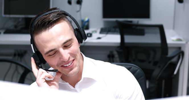 young smiling male call centre operator doing his job with a headset