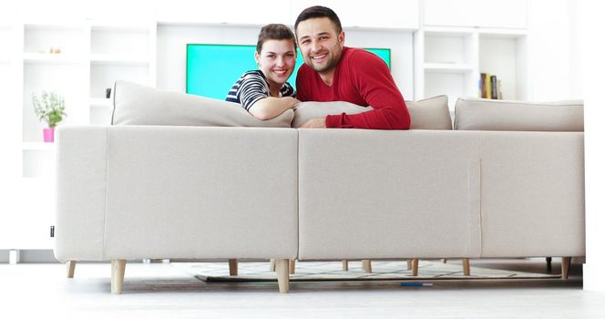 Young couple on the sofa watching television together in their luxury home