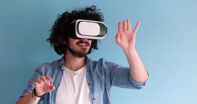 Happy man getting experience using VR headset glasses of virtual reality, isolated on blue background