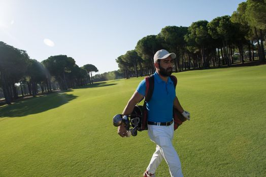 handsome middle eastern golf player carrying and bag  and walking at course on beautiful morning sunrise