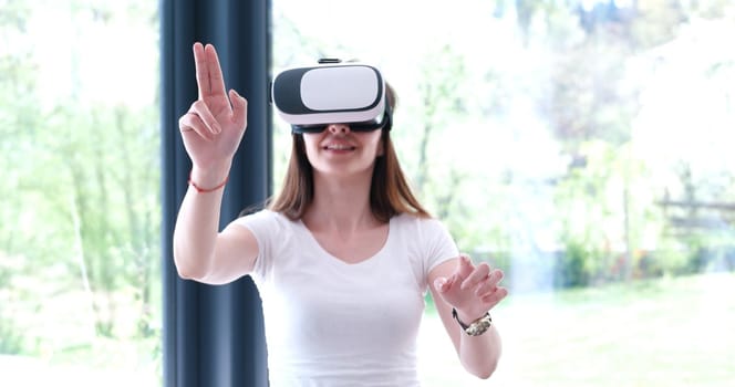 Smile happy woman getting experience using VR-headset glasses of virtual reality at home