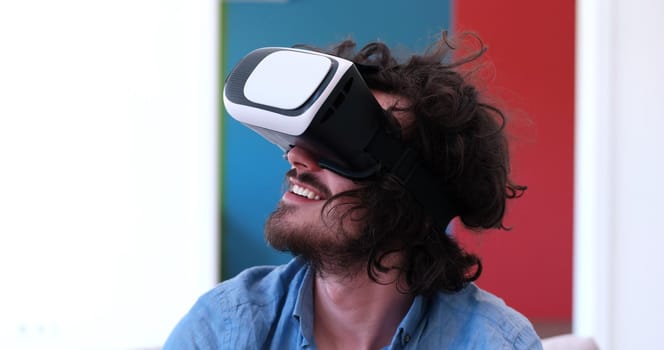 happy man getting experience using VR-headset glasses of virtual reality at home