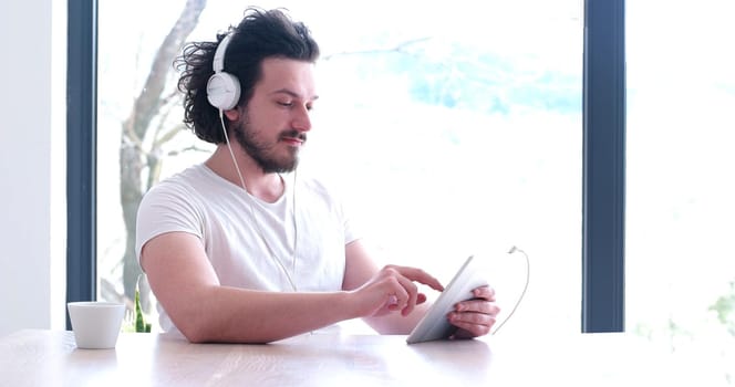 Handsome young man listenig music on tablet at  home