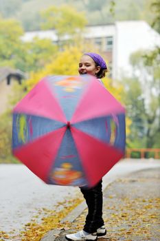 happy girl with umbrella outdoor in park on autumn season rain day