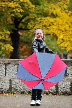 happy girl with umbrella outdoor in park on autumn season rain day