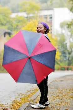 happy girl with umbrella outdoor in park on autumn season rain day