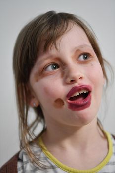 Cute little preschool girl playing with mommy's make up. Fashion experiment little child applying makeup lipstick and shadow on face, staying at home in corona virus quarantine.