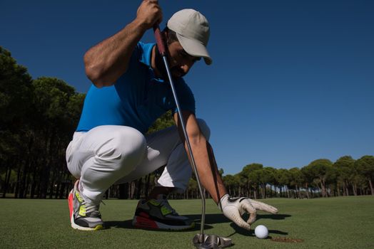 close up of man's hand putting golf ball in hole at course