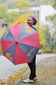 happy girl with umbrella outdoor in park on autumn season rain day