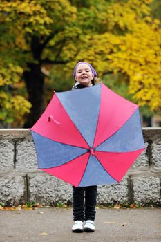 happy girl with umbrella outdoor in park on autumn season rain day