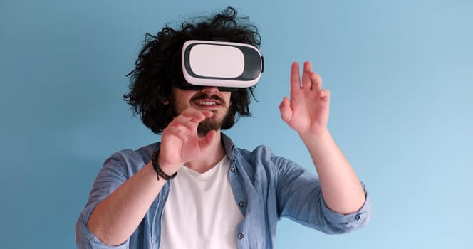 Happy man getting experience using VR headset glasses of virtual reality, isolated on blue background