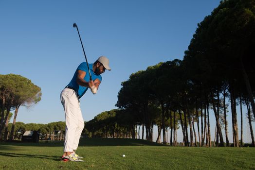 handsome sporty man, golf player hitting shot with club on course at beautiful morning