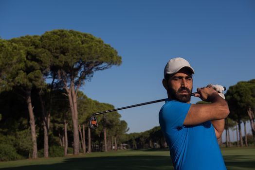 golf player hitting shot with club on course at beautiful morning with sun flare in background