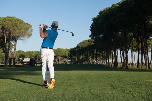 golf player hitting shot with driver on course at beautiful sunny day