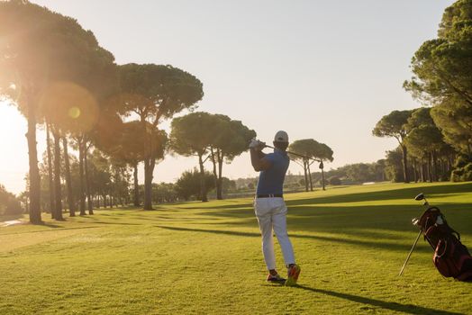 golf player hitting shot with driver on course at beautiful sunny day