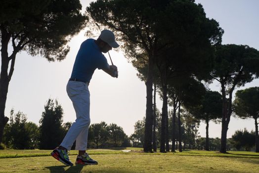 golf player hitting shot with driver on course at beautiful sunny day