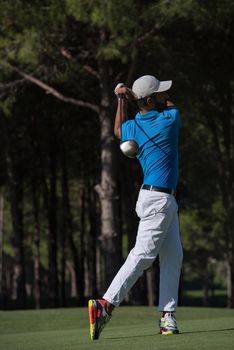 golf player hitting shot with driver on course at beautiful sunny day