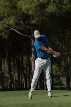 golf player hitting shot with driver on course at beautiful sunny day