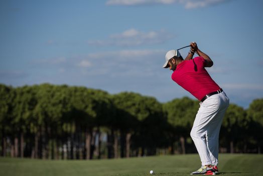 golf player hitting shot with driver on course at beautiful sunny day