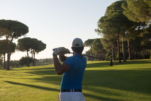 handsome sporty man, golf player hitting shot with club on course at beautiful morning