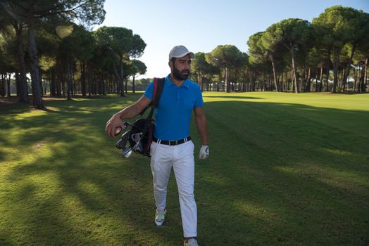 handsome middle eastern golf player carrying and bag  and walking at course on beautiful morning sunrise