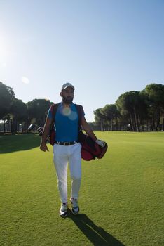 handsome middle eastern golf player carrying and bag  and walking at course on beautiful morning sunrise