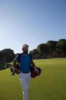 handsome middle eastern golf player carrying and bag  and walking at course on beautiful morning sunrise