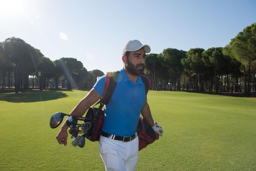 handsome middle eastern golf player carrying and bag  and walking at course on beautiful morning sunrise