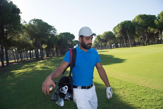 handsome middle eastern golf player carrying and bag  and walking at course on beautiful morning sunrise