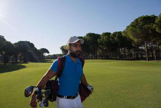 handsome middle eastern golf player carrying and bag  and walking at course on beautiful morning sunrise