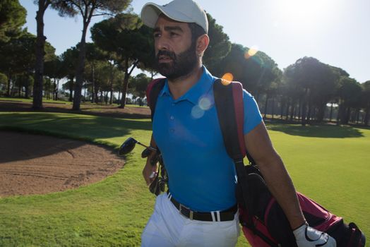 handsome middle eastern golf player carrying and bag  and walking at course on beautiful morning sunrise