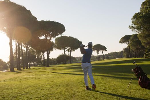 golf player hitting shot with driver on course at beautiful sunny day