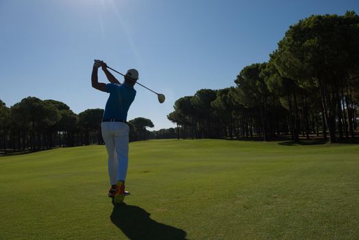 golf player hitting shot with driver on course at beautiful sunny day