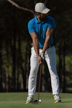 golf player hitting shot with club on course at beautiful morning