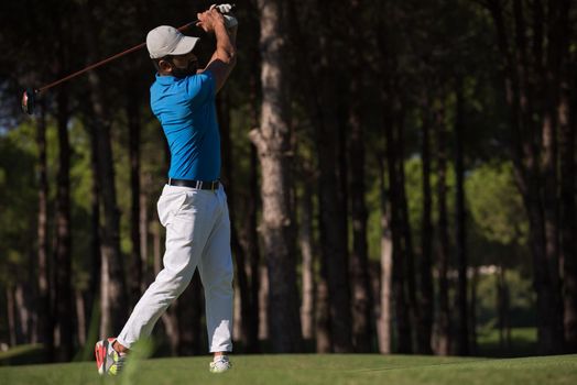 golf player hitting shot with club on course at beautiful morning