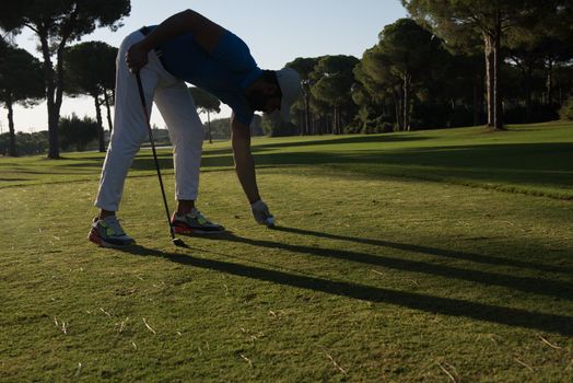 golf player hitting shot with club on course at beautiful morning with sun flare in background