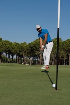 golf player hitting shot with driver on course at beautiful sunny day