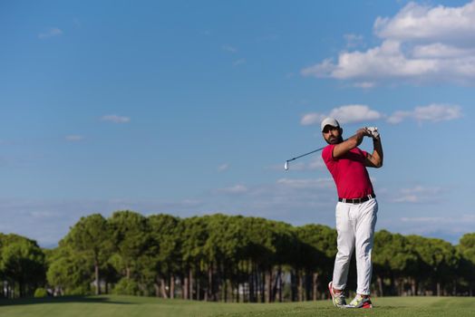 golf player hitting shot with driver on course at beautiful sunny day