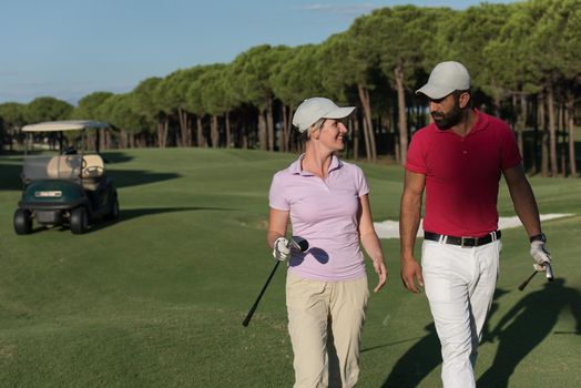 young couple walking to next hole on golf course. man carrying golf bag